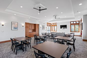 A room with tables and chairs and a ceiling fan.